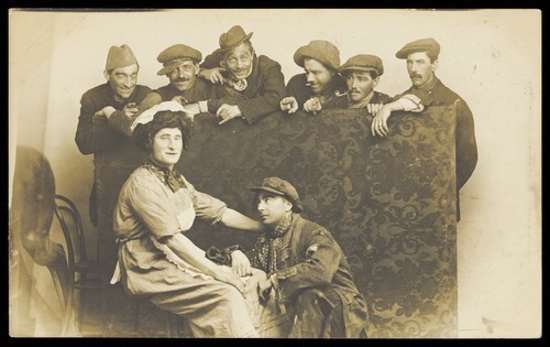 Download the full-sized image of Actors gathered around a man in drag. Photographic postcard by The Fancy Dress Studio, 191-.