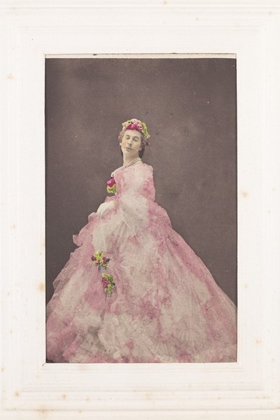 Download the full-sized image of Francis Cowley Burnand, in drag, poses wearing a large pink dress with flowers in his hair. Photograph, ca. 1855.