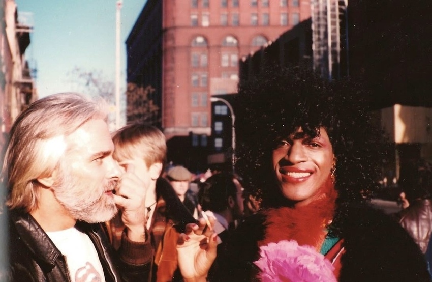 Download the full-sized image of A Photograph of Marsha P. Johnson Wearing Red Lipstick, a Red Feather Boa, a Pink Flower, and Smoking a Cigarette
