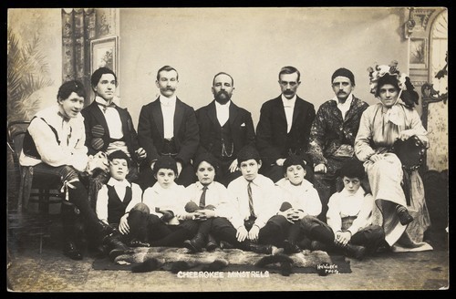 Download the full-sized image of Actors, one in drag, pose for a group portrait as "Cheerokee Minstrels". Photographic postcard by H..E. Howorth, 1904.