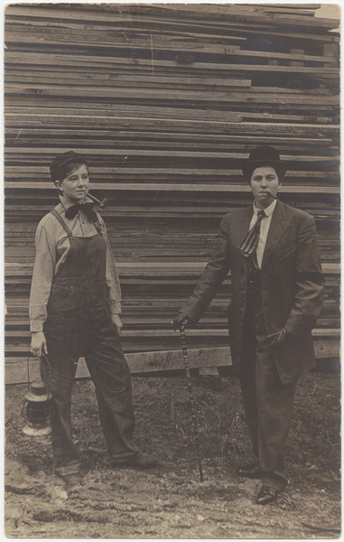 Download the full-sized image of Male impersonators in front of stack of lumber